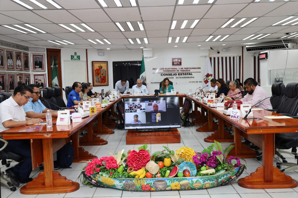 Mesa en U del Consejo Estatal del IEPC Tabasco en sesión extraordinaria, con una canoa de flores y frutas al centro