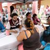 Servidores públicos del Gobierno de Tabasco atienden trámites de dos mujeres en una mesa durante una audiencia pública