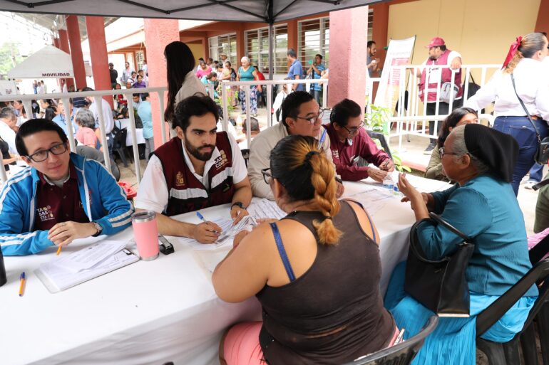 Servidores públicos del Gobierno de Tabasco atienden trámites de dos mujeres en una mesa durante una audiencia pública