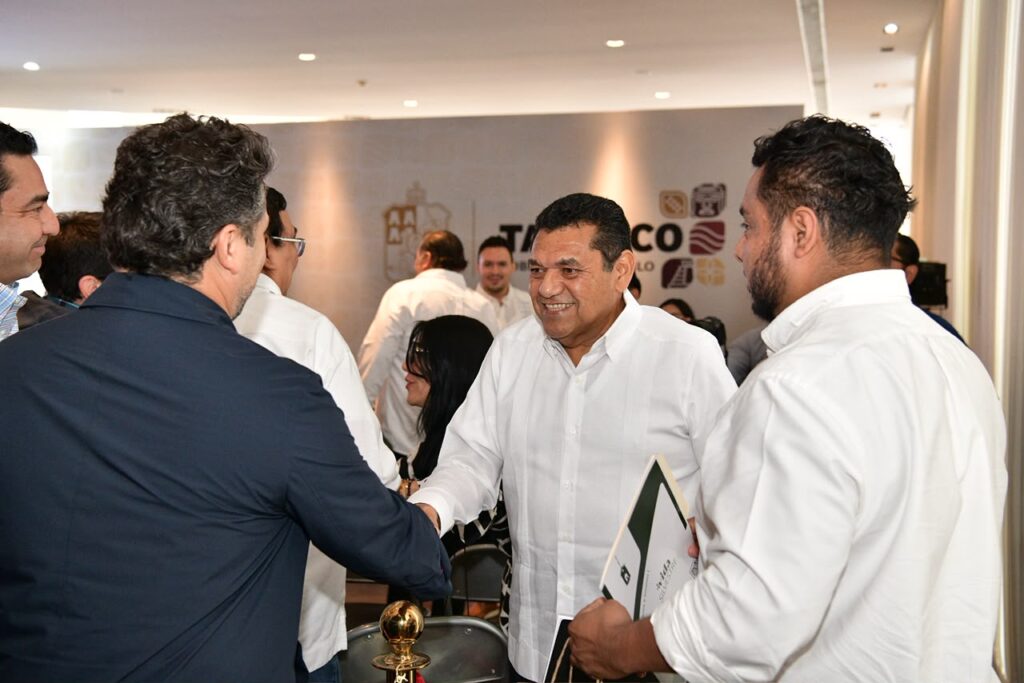 Javier May Rodríguez estrecha la mano de un participante durante un encuentro con representantes empresariales en Tabasco.