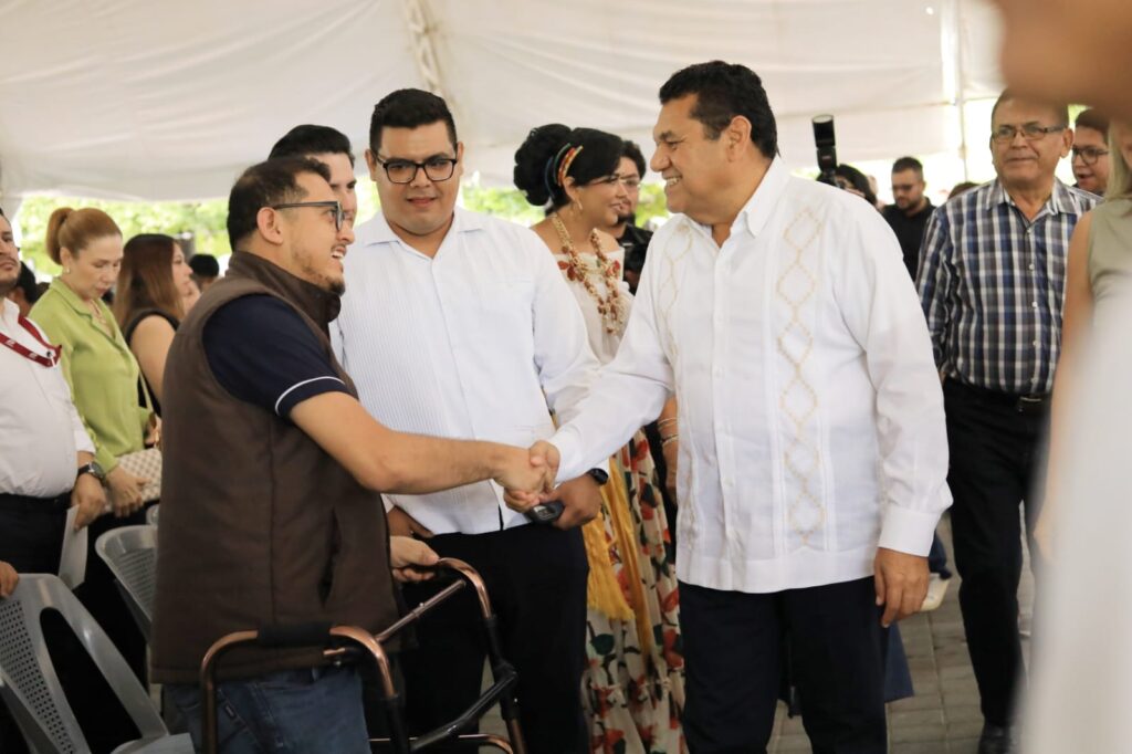 Javier May Rodríguez saluda a un asistente que utiliza una andadera durante la Feria Nacional de Empleo en Comalcalco.
