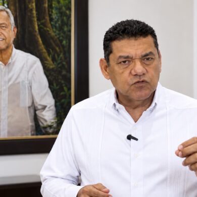 Javier May Rodríguez emite un mensaje por los 15 años de Morena, frente a un retrato de Andrés Manuel López Obrador.