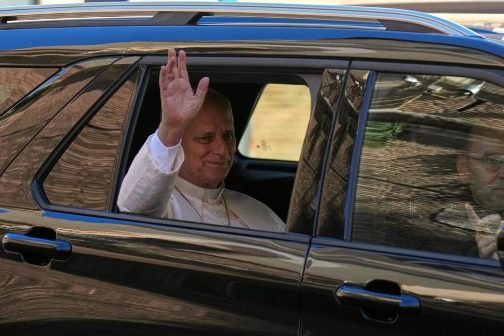 El papa León XIV saluda desde la ventanilla de un vehículo negro durante uno de sus desplazamientos públicos.