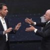Lula da Silva y Flávio Bolsonaro frente a frente durante un debate presidencial en Brasil, con gestos de confrontación.