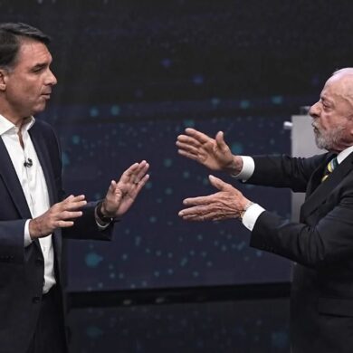 Lula da Silva y Flávio Bolsonaro frente a frente durante un debate presidencial en Brasil, con gestos de confrontación.