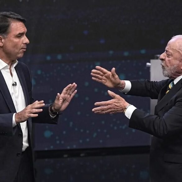 Lula da Silva y Flávio Bolsonaro frente a frente durante un debate presidencial en Brasil, con gestos de confrontación.