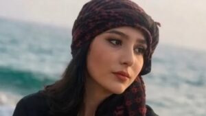 Retrato de Najmeh Amini, estudiante iraní de 23 años condenada a muerte por blasfemia en redes sociales, con pañuelo oscuro y el mar al fondo