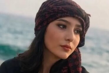 Retrato de Najmeh Amini, estudiante iraní de 23 años condenada a muerte por blasfemia en redes sociales, con pañuelo oscuro y el mar al fondo