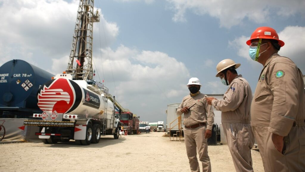 Estructura industrial petrolera con una manta de Pemex y su emblema corporativo en una instalación de hidrocarburos.