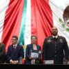 Representante de la embajada de Israel sostiene un reconocimiento de Policías Celestiales durante una ceremonia en la Cámara de Diputados, ante la bandera de México.