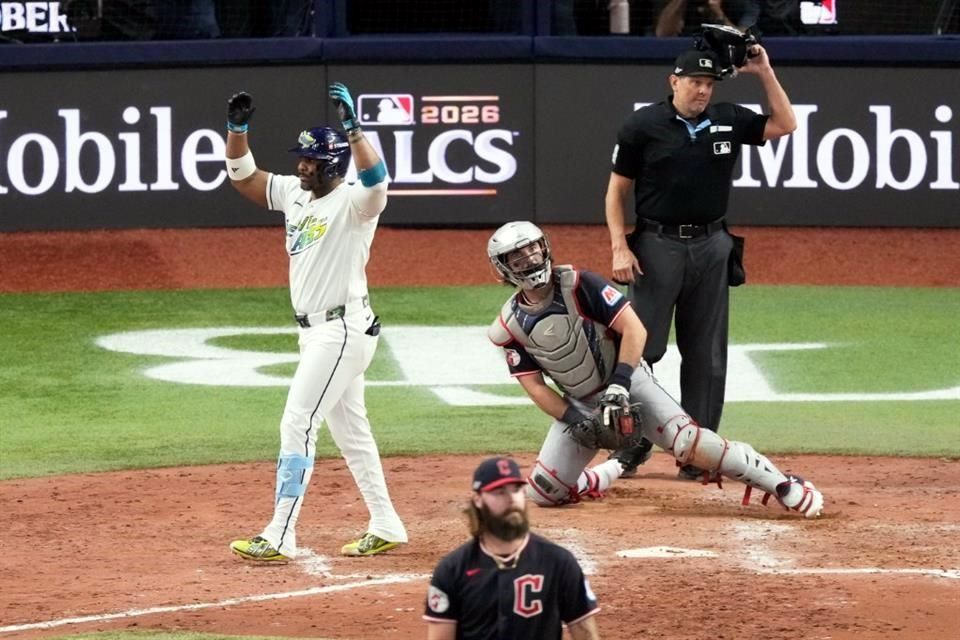 Un bateador de los Rays levanta los brazos en el plato ante el cátcher de Cleveland y el umpire, durante el sexto juego de la Serie de Campeonato de la Americana 2026