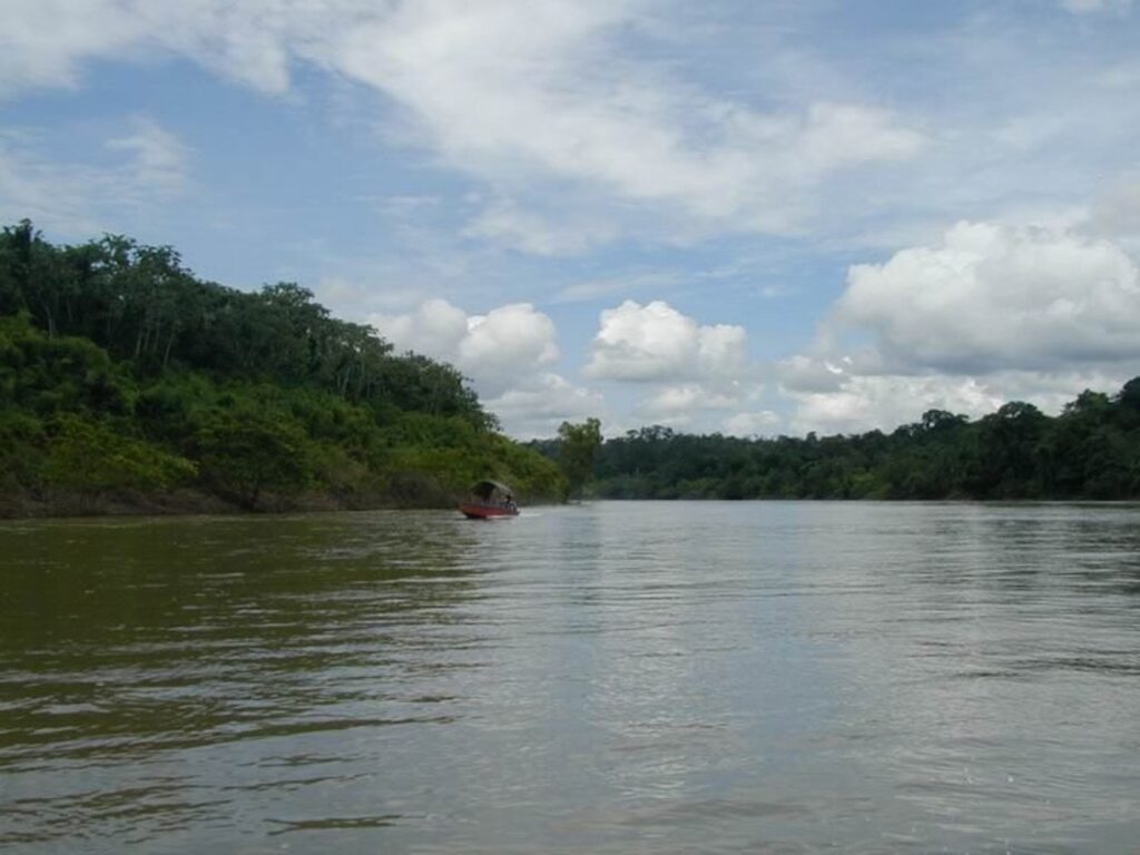 Río Usumacinta con selva en ambas orillas y una lancha a lo lejos, bajo un cielo con nubes