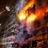 Edificio envuelto en llamas durante un incendio de gran magnitud, mientras bomberos utilizan una plataforma elevada para combatir el fuego.