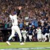 Un lanzador de los Rays de Tampa Bay levanta los brazos mientras sus compañeros salen corriendo del banquillo y la tribuna celebra el pase a la Serie Mundial