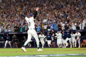 Un lanzador de los Rays de Tampa Bay levanta los brazos mientras sus compañeros salen corriendo del banquillo y la tribuna celebra el pase a la Serie Mundial