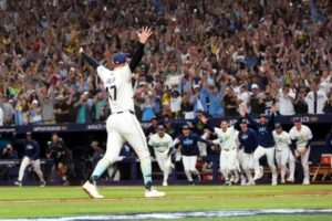 Un lanzador de los Rays de Tampa Bay levanta los brazos mientras sus compañeros salen corriendo del banquillo y la tribuna celebra el pase a la Serie Mundial