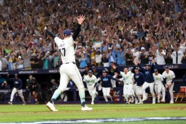 Un lanzador de los Rays de Tampa Bay levanta los brazos mientras sus compañeros salen corriendo del banquillo y la tribuna celebra el pase a la Serie Mundial