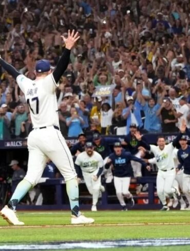 Un lanzador de los Rays de Tampa Bay levanta los brazos mientras sus compañeros salen corriendo del banquillo y la tribuna celebra el pase a la Serie Mundial