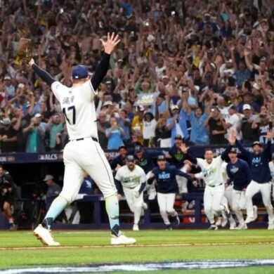 Un lanzador de los Rays de Tampa Bay levanta los brazos mientras sus compañeros salen corriendo del banquillo y la tribuna celebra el pase a la Serie Mundial