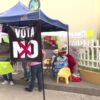Plantón de trabajadores del IMSS bajo una carpa azul con una pancarta negra que dice «Vota NO» y letreros que exigen salarios dignos.