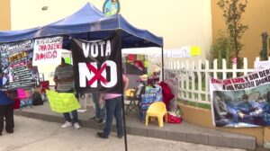 Plantón de trabajadores del IMSS bajo una carpa azul con una pancarta negra que dice «Vota NO» y letreros que exigen salarios dignos.