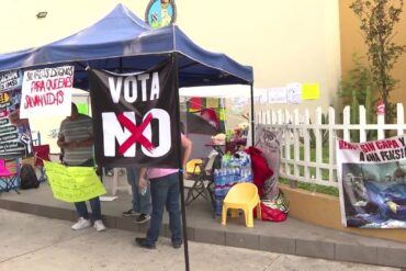 Plantón de trabajadores del IMSS bajo una carpa azul con una pancarta negra que dice «Vota NO» y letreros que exigen salarios dignos.