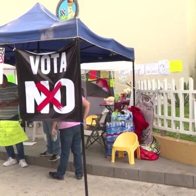Plantón de trabajadores del IMSS bajo una carpa azul con una pancarta negra que dice «Vota NO» y letreros que exigen salarios dignos.