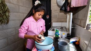 Niña prepara alimentos en una cocina doméstica, imagen ilustrativa de las tareas del hogar que aborda el reportaje sobre trabajo infantil en Tabasco.