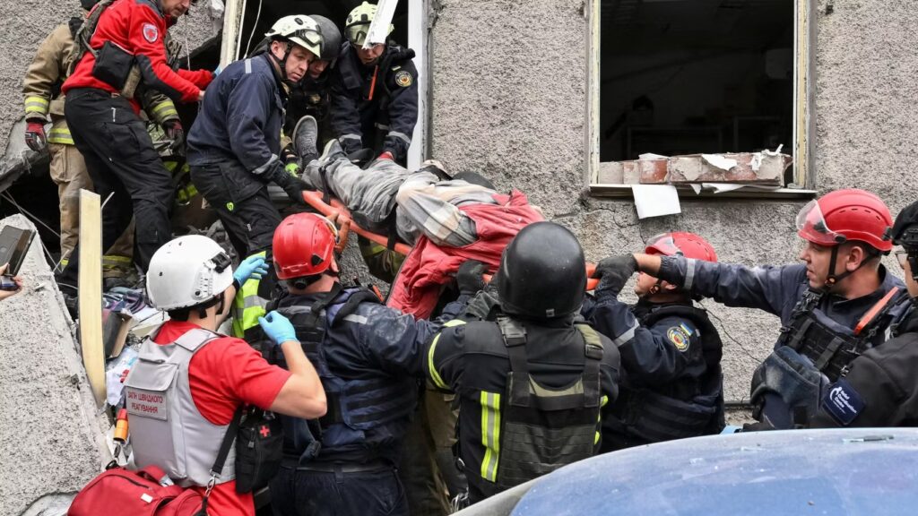Equipos de emergencia y rescatistas trasladan a una persona en camilla desde un edificio dañado durante la guerra en Ucrania.