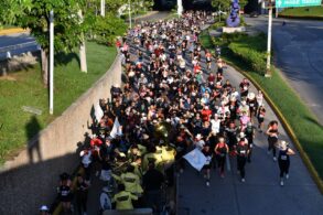Multitud de corredores con sombreros y paliacates avanza junto a una banda con uniformes amarillos en la VaqueRun Tabasco 2026
